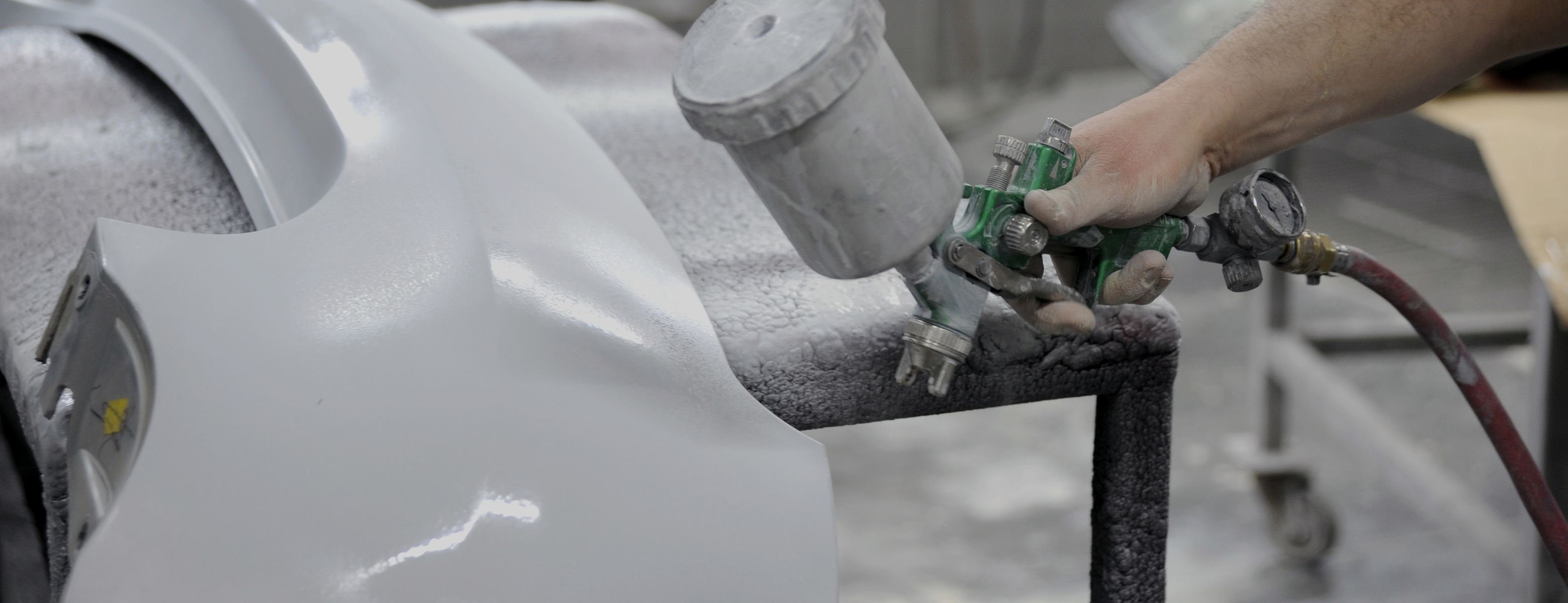 Aplica&ccedil;&atilde;o de revestimento autom&oacute;vel com pistola de pintura em ambiente industrial, ilustrando solu&ccedil;&otilde;es t&eacute;cnicas testadas diretamente na linha de produ&ccedil;&atilde;o.